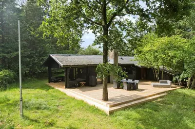 a cabin with a wooden deck and a tree at BL1494-Saltum-Viborgvej-6 in Saltum