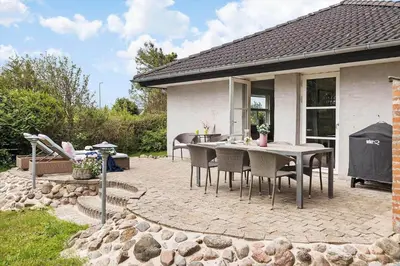 a patio with a table and chairs in front of a house at BL1206-Blokhus-Blaabaervej-6 in Blokhus