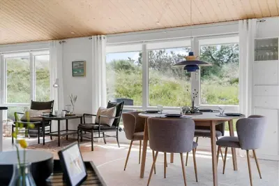 a dining room with tables and chairs and windows at BL1371-Blokhus-Sletten-10-A in Blokhus