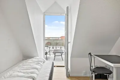 a bedroom with a bed and a desk and a balcony at BL1260-Blokhus-Strandvejen-14-Lejl-9 in Blokhus