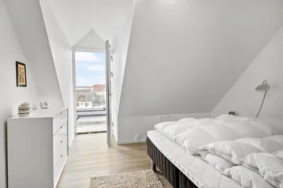 a white bedroom with a large bed and a window at BL1260-Blokhus-Strandvejen-14-Lejl-9 in Blokhus