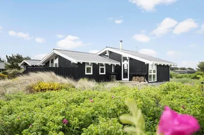 a black house with white windows and a field of flowers at BL687-Saltum-Porsevej-16 in Saltum