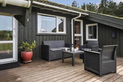 a wooden deck with chairs and a table on it at BL1781-Saltum-Ornebjergvej-26 in Saltum