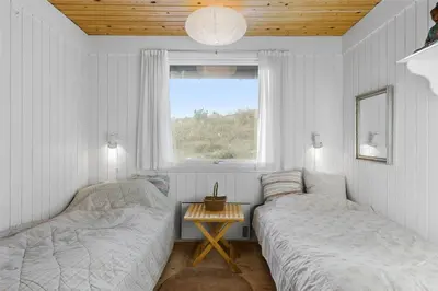 two beds in a room with a window and a table at BL1677-Saltum-Sikahjortvej-6 in Saltum