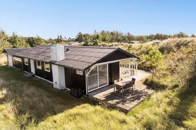 a house with a deck in the middle of a field at BL1677-Saltum-Sikahjortvej-6 in Saltum
