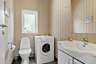 a bathroom with a washing machine and a sink at BL1700-Blokhus-Bloksbjerg-55 in Blokhus