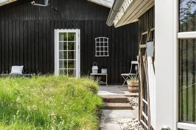 a black house with a white door and a patio at BL1082-Blokhus-Klintevej-12 in Blokhus