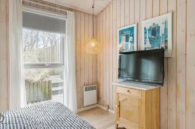 a bedroom with a flat screen tv and a window at BL1156-Blokhus-Ankerhusvej-44 in Blokhus
