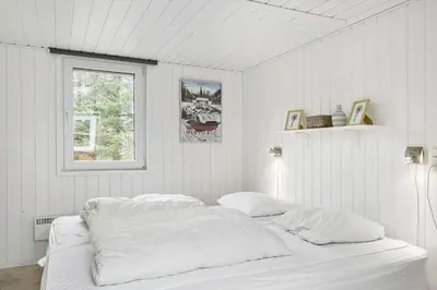 a white bedroom with a bed with white sheets at BL253-Blokhus-Jaegerbakken-9 in Blokhus