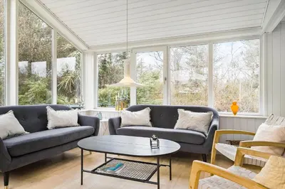 a living room with couches and a table and windows at BL253-Blokhus-Jaegerbakken-9 in Blokhus