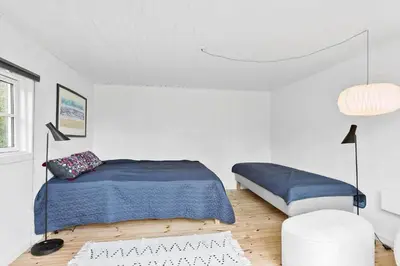 a white bedroom with a blue bed and a white chair at BL1335-Blokhus-Havorns-Alle-32 in Blokhus
