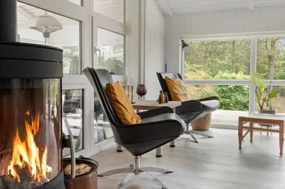 a fireplace in a living room with chairs and a table at BL1200-Blokhus-Plantagevej-6-C in Blokhus