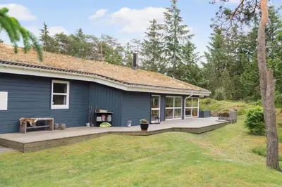 a blue house with a large deck in the yard at BL1200-Blokhus-Plantagevej-6-C in Blokhus