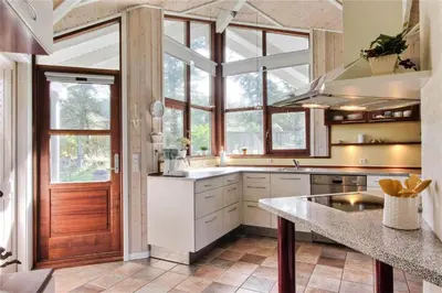 a large kitchen with a large window and a door at BL861-Blokhus-Pirupshvarrevej-49 in Blokhus