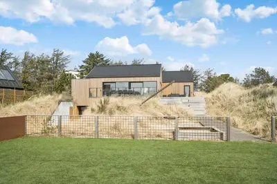 a house on top of a hill with a fence at BL1405-Blokhus-Sletten-12 in Blokhus