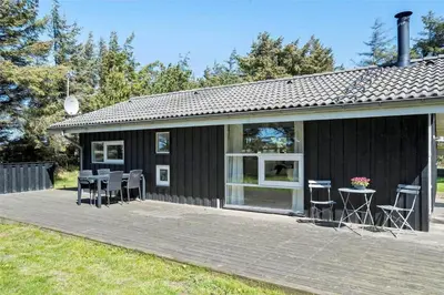 a black house with chairs and a table on a deck at BL583-Saltum-Saltum-Strandvej-210 in Saltum