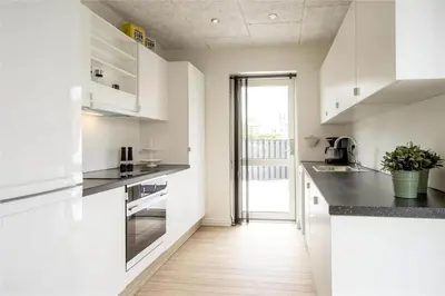 a kitchen with white cabinets and a wooden floor at BL139-Blokhus-Klitvejen-4-A in Blokhus