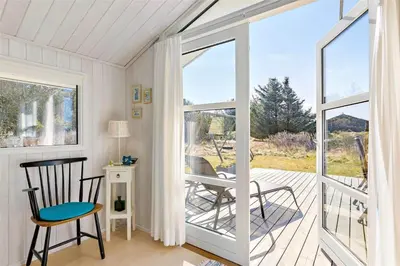 a screened in porch with chairs and a sliding glass door at BL418-Pandrup-Hunetorp-Klitvej-141 in Pandrup