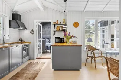 a kitchen with gray cabinets and a table and chairs at BL1756-Blokhus-Bregnehojvej-7-A in Blokhus