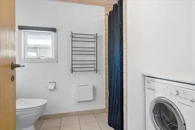 a bathroom with a toilet and a washing machine at BL1601-Blokhus-Kristinesvej-15 in Blokhus