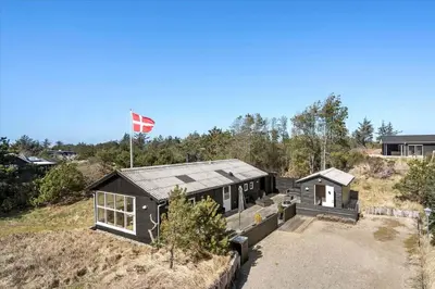 a house on top of a hill with a flag at BL1601-Blokhus-Kristinesvej-15 in Blokhus