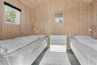 two beds in a room with wooden walls at BL1601-Blokhus-Kristinesvej-15 in Blokhus
