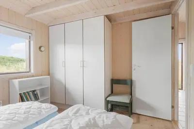a bedroom with a bed and a chair and a window at BL1591-Pandrup-Ferborgvej-54 in Pandrup
