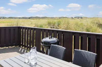 a grill on a deck with a table and chairs at BL1591-Pandrup-Ferborgvej-54 in Pandrup