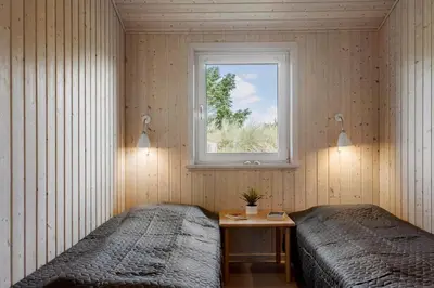 two beds in a room with a window at BL1564-Blokhus-Ved-Skoven-8 in Blokhus