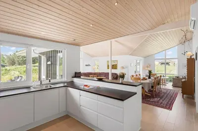 a kitchen with white cabinets and a dining room at BL1564-Blokhus-Ved-Skoven-8 in Blokhus