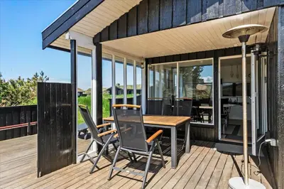 an outdoor deck with a wooden table and chairs at BL411-Pandrup-Hunetorp-Klitvej-223 in Pandrup