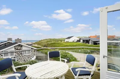 a balcony with a table and chairs and a view of the ocean at BL1222-Blokhus-Strandvejen-13-B in Blokhus