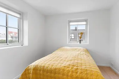 a bed in a white room with two windows at BL1222-Blokhus-Strandvejen-13-B in Blokhus