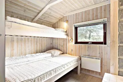 a bedroom with two bunk beds and a window at BL236-Blokhus-Pirupshvarrevej-27 in Blokhus