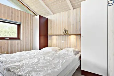 a bedroom with a large white bed and a window at BL236-Blokhus-Pirupshvarrevej-27 in Blokhus