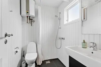 a white bathroom with a toilet and a sink at BL1612-Blokhus-Jens-Baerentsvej-3 in Blokhus