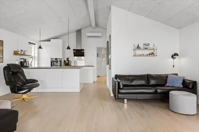a living room with a black leather couch and a kitchen at BL1315-Saltum-Kordalsvej-43 in Saltum