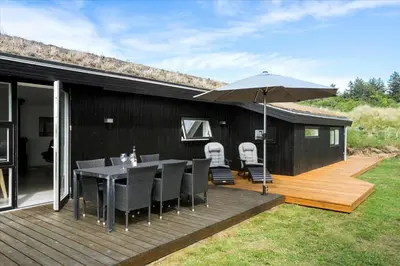 a wooden deck with a table and an umbrella at BL1315-Saltum-Kordalsvej-43 in Saltum