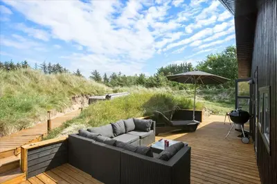 a patio with a couch and an umbrella on a deck at BL1315-Saltum-Kordalsvej-43 in Saltum