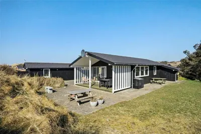 a black and white house with a picnic table and benches at BL1616-Blokhus-Moreavej-18 in Blokhus