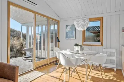 a dining room with a table and white chairs at BL1616-Blokhus-Moreavej-18 in Blokhus