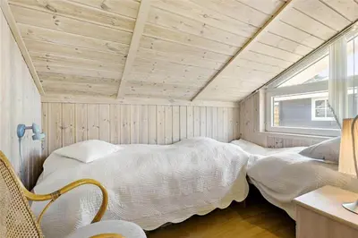 a bedroom with a bed in a room with a window at BL791-Blokhus-Paa-Bakken-3 in Blokhus