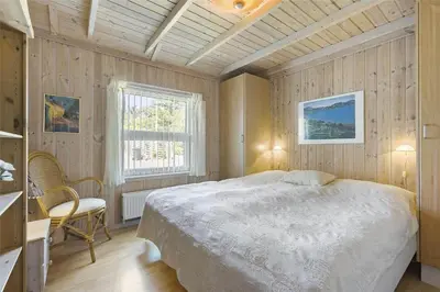 a bedroom with a large bed and a window at BL791-Blokhus-Paa-Bakken-3 in Blokhus