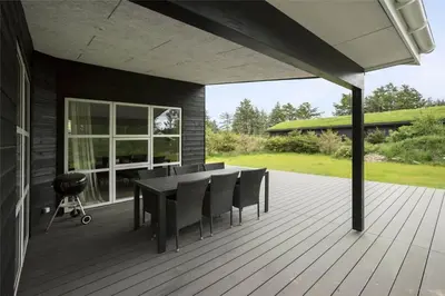 a patio with a table and chairs on a deck at BL1134-Blokhus-Bloksbjerg-17-B in Blokhus