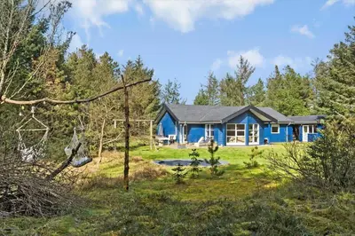 a blue house in the middle of a forest at BL1328-Saltum-Kvanbaekvej-33 in Saltum