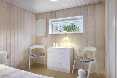 a bedroom with two chairs and a dresser and a window at BL1447-Blokhus-Skraavejen-11 in Blokhus