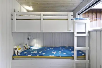 a bunk bed in a room with a ladder at BL1447-Blokhus-Skraavejen-11 in Blokhus