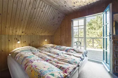 a bedroom with a bed in a room with a window at BL1384-Blokhus-Kragebak-7 in Blokhus