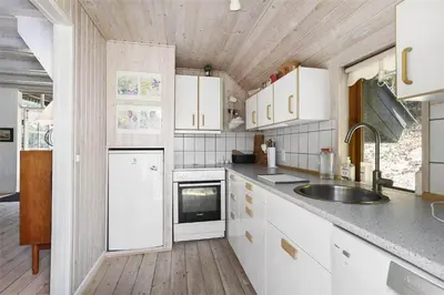 a kitchen with white cabinets and a sink at BL1384-Blokhus-Kragebak-7 in Blokhus