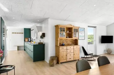 a kitchen with a wooden cabinet and a table at BL1377-Blokhus-Valmuemarken-37 in Blokhus